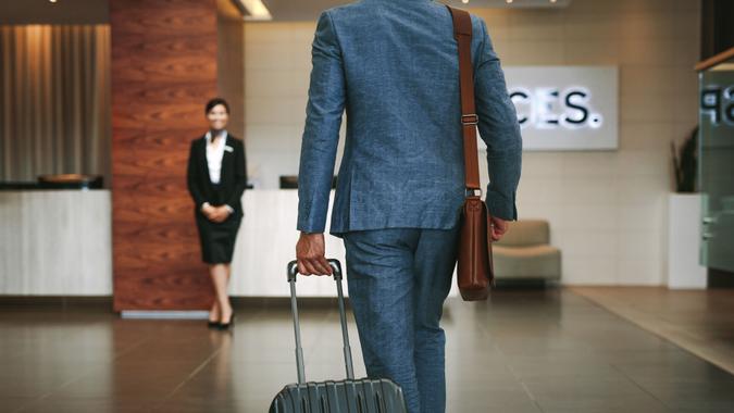 Businessman carrying suitcase while walking in hotel lobby.