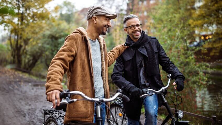 Smiling friends standing with bicycles.