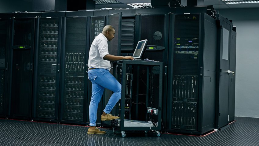 Shot of an IT technician using a computer while working in a data center.