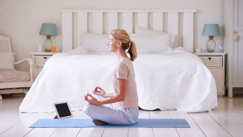 Woman With Digital Tablet Using Meditation App In Bedroom.