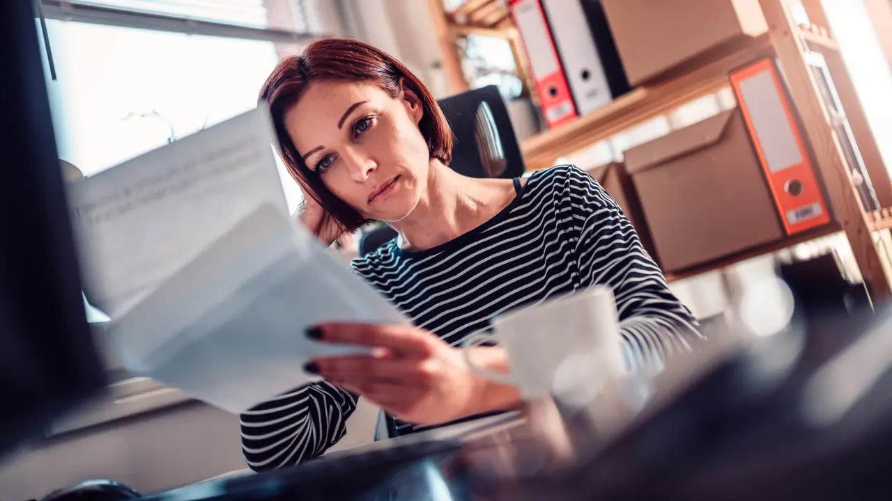 Worried woman sitting by the window reading mail in the office.