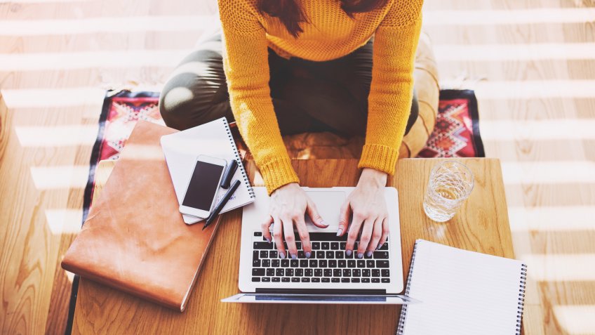 Unrecognizable young woman with laptop at home.