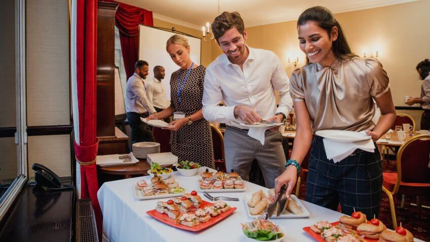 Front view of business people getting food from a buffet at a conference meeting.