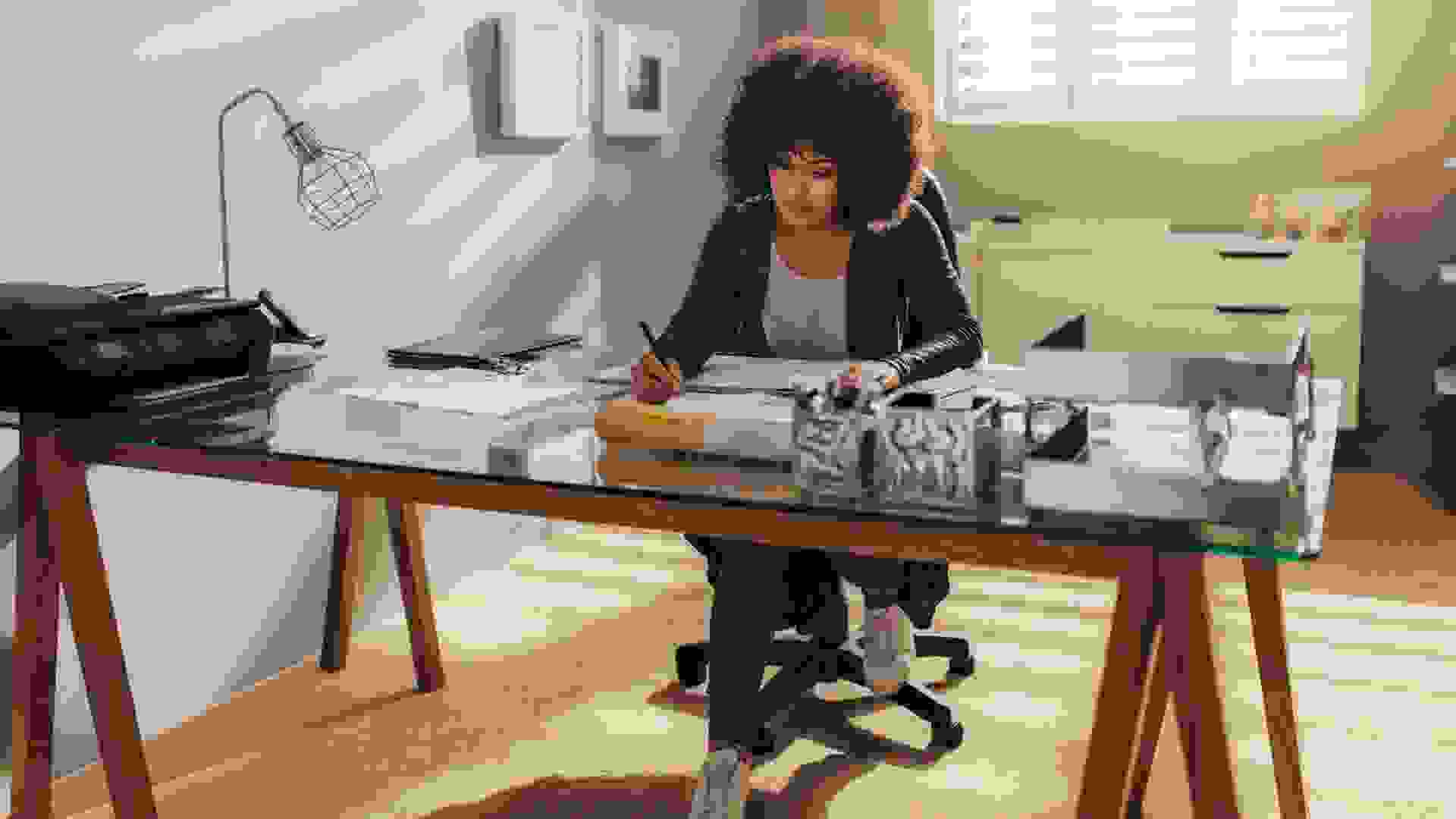 African woman working on new building plans while sitting at her desk.