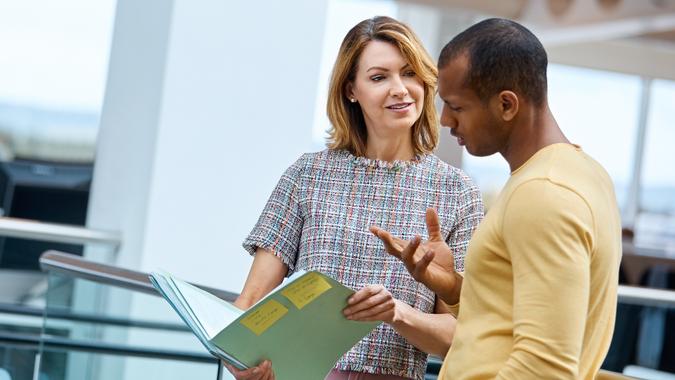 Mature businesswoman holding a file while talking to a colleague in charge.