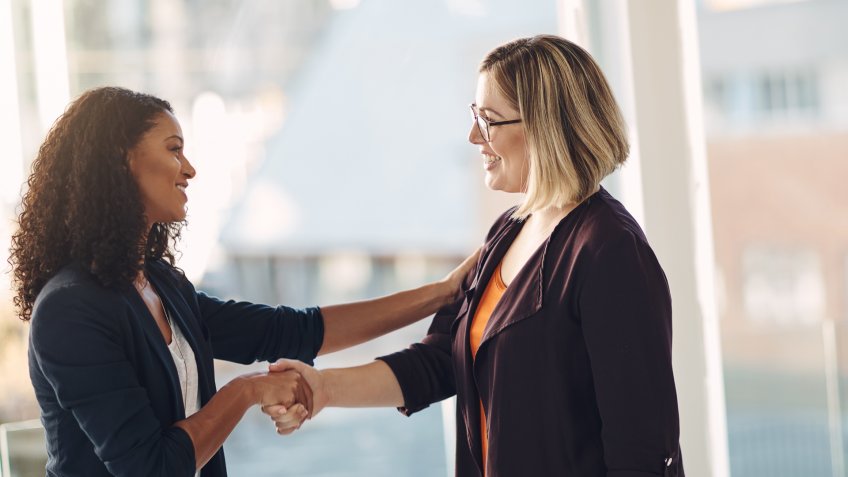 Shot of two businesswomen shaking hands in a modern office.