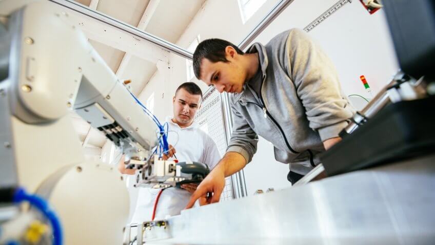 Engineers working on development of automated production line with robotic parts and applied software in order to increase productivity.