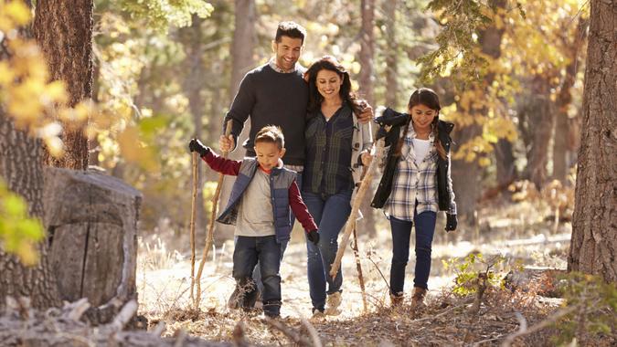 Happy Hispanic family with two children walking in a forest.