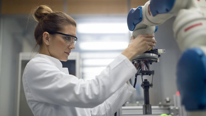 Mid adult female electrical engineer working with robotic arm.