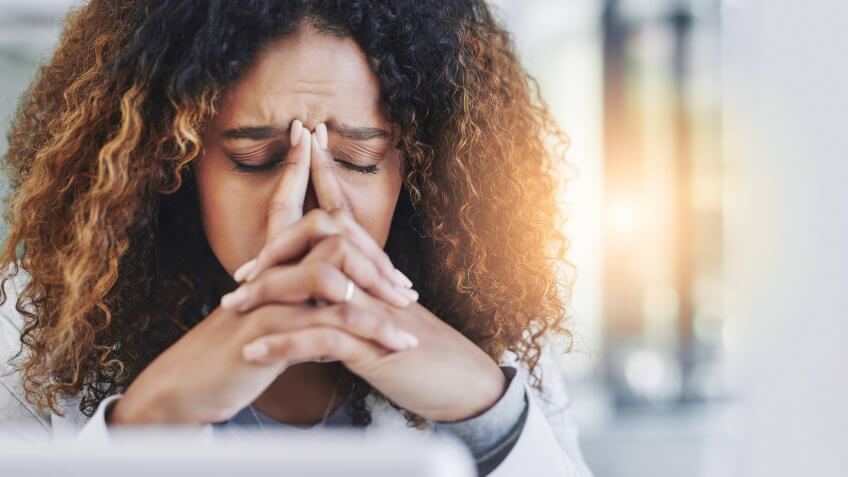 Shot of a young businesswoman looking stressed out in an office.
