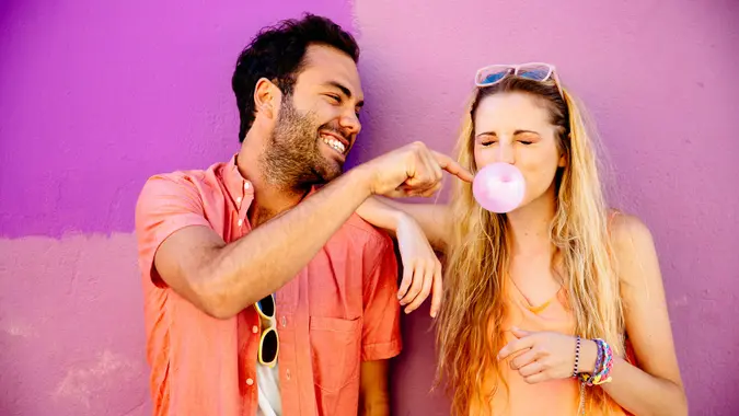 Happy playful young couple against pink background.