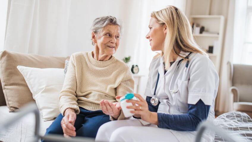 A young health visitor explaining a senior woman how to take medicine and pills.
