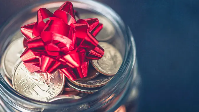 Christmas money jar with American currency and topped with bow.