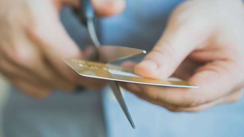 Man cutting gold credit card with scissors.