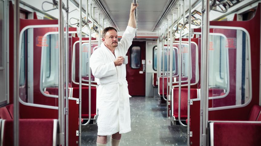 Early commuter wearing bathrobe and slippers on the underground train.
