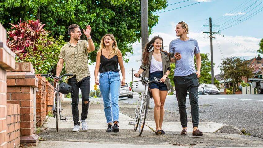 Four Australian friends walking in the street of Sydney on a sunny day.