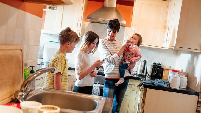 Multitasking mum is tending to all of her children at once in the kitchen of their home.