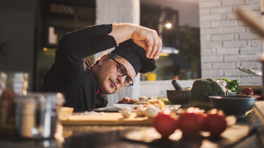 Photo of an experienced chef adding spices to the meal he is preparing.