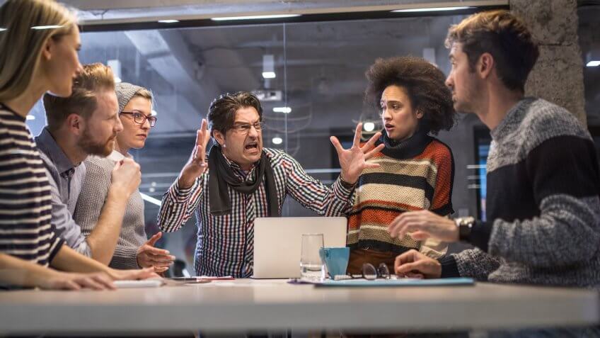 Angry manager shouting at his coworkers during a meeting in the office.