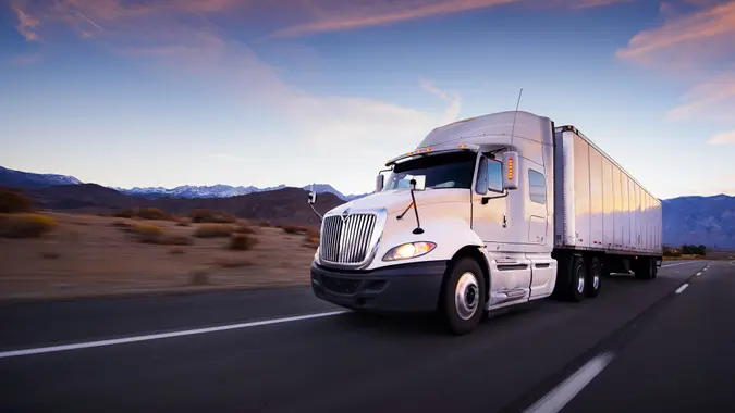 Truck and highway at sunset - transportation background.