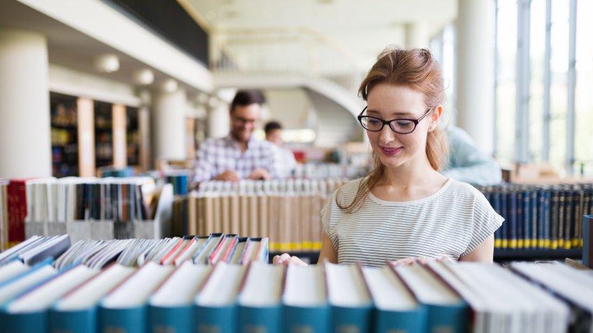 smiling girl reading book in library