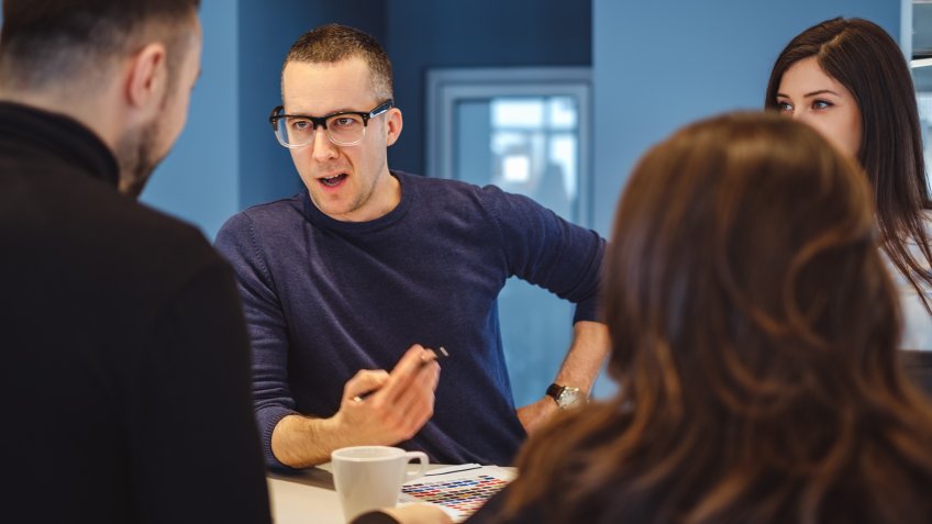 Man with glasses aggressively talking at the office meeting to his colleagues.