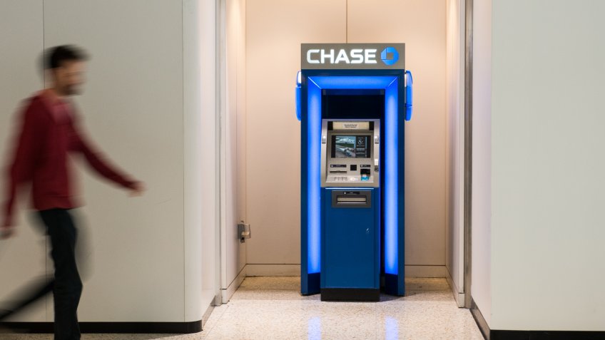 Houston, TX, USA - November 19, 2015: Man carrying a red cabin size luggage, walking towards a Chase Bank ATM.