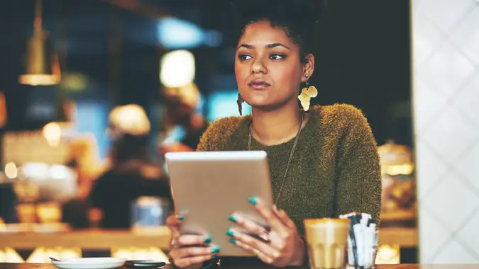Shot of an attractive young woman looking thoughtful while using a digital tablet in a cafe.
