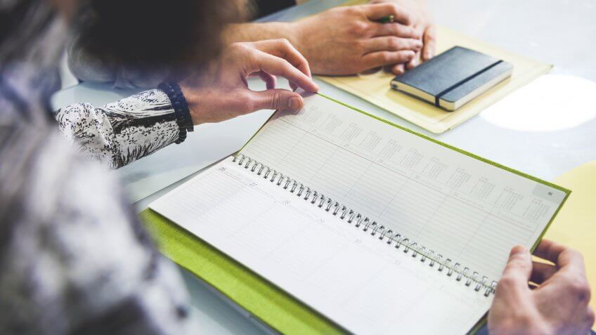 During a business meeting in the office, people setting up the week schedule on calendar.