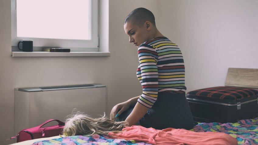 Sad woman suffering from cancer sitting on bed before leaving hospital.