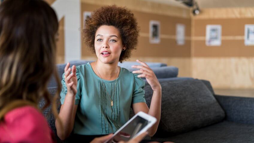 A photo of young businesswoman talking with colleague.