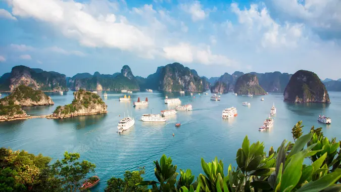 Panorama of Halong Bay in Vietnam at sunset with anchored tourist ships photographed from atop a cliff.