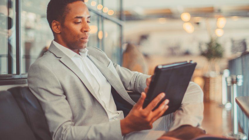 Young businessman using digital tablet in hotel lobby.