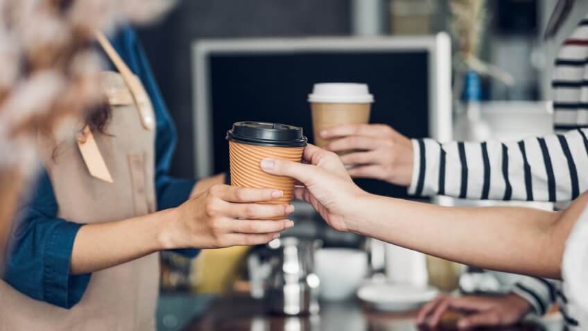 Barista served take away hot coffee cup to customer at counter bar in cafe restaurant,coffee shop business owner concept,Service mind waitress.