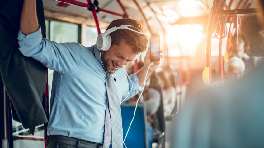 Close up of a businessman listening to music while riding in a bus.