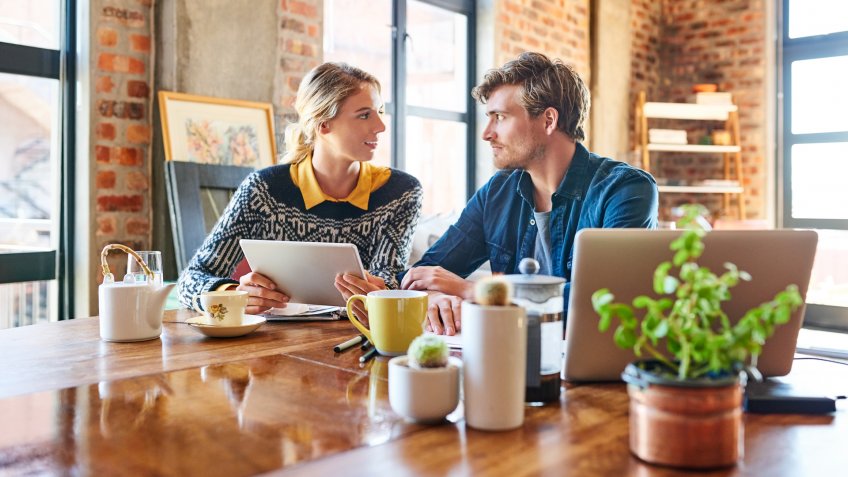 Young couple with digital tablet having discussion at table.
