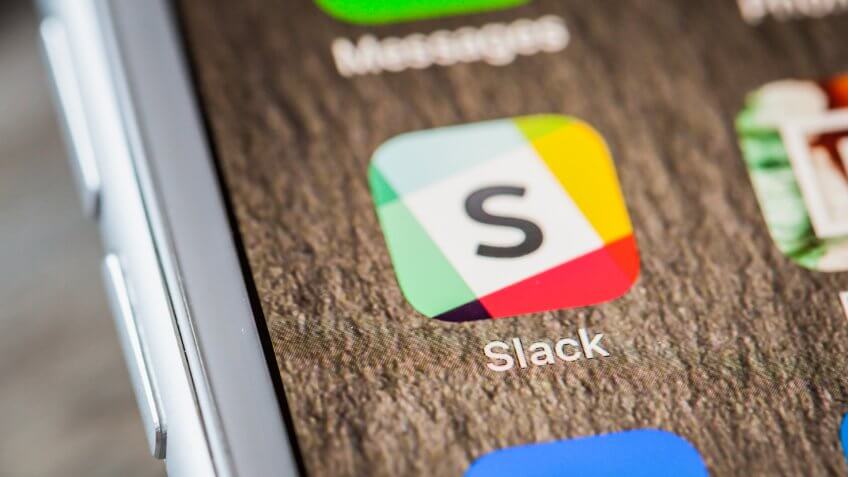 BERLIN, GERMANY - JUNE 6, 2018: Close up to Slack team chat app on the screen of an iPhone 7 Plus with personalized background.