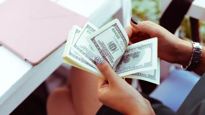 Woman counting hundred dollar bills in her hands