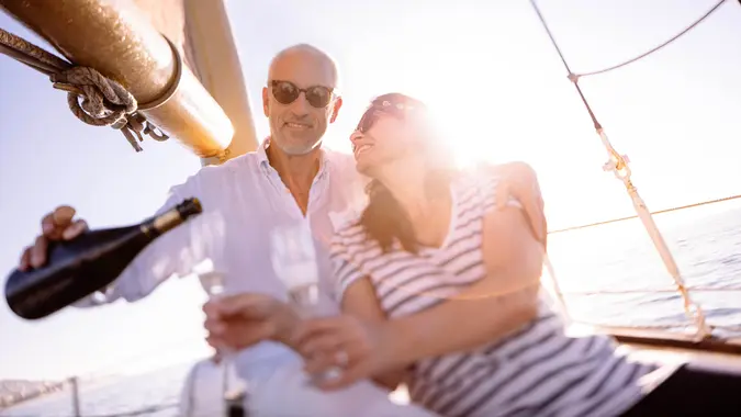 Loving mature couple enjoying a romantic sunset cruise on a yacht at sunset with champagne to celebrate a special occasion on holiday.
