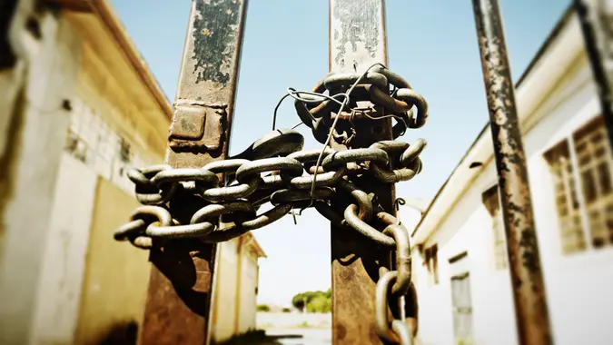The gate to a disused industrial building is barred, chained and locked.