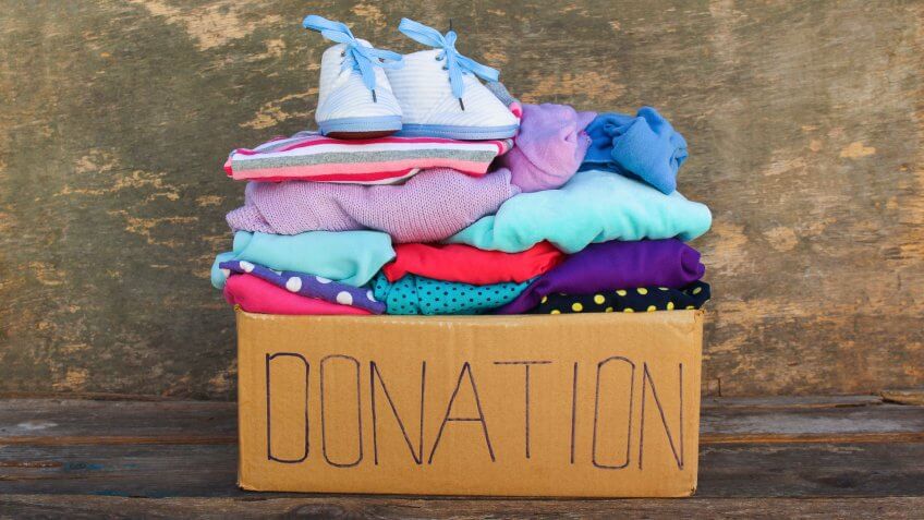 Donation box with children's things on wooden background.