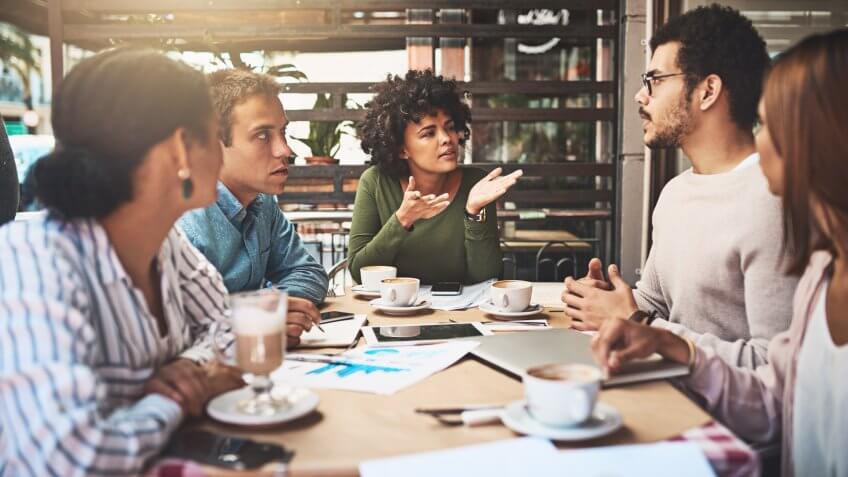 Shot of a group of focused young work colleagues having a discussion at a meeting together while being seated around a table.