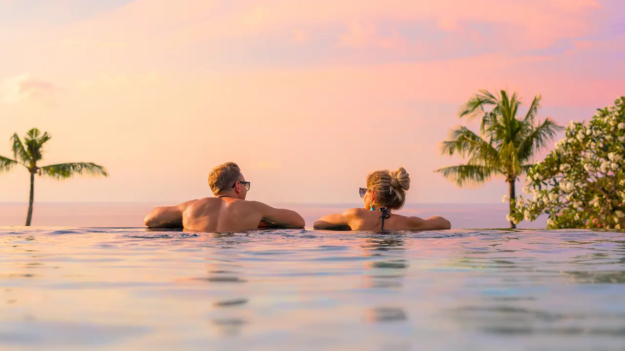 Romantic couple looking at beautiful sunset in luxury infinity pool.