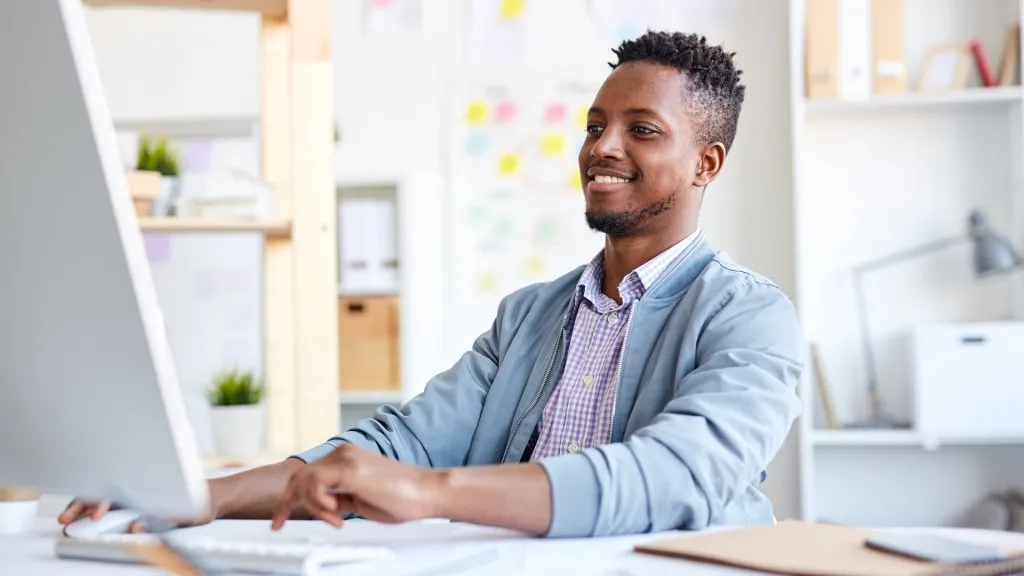 Positive African graphic designer using computer.