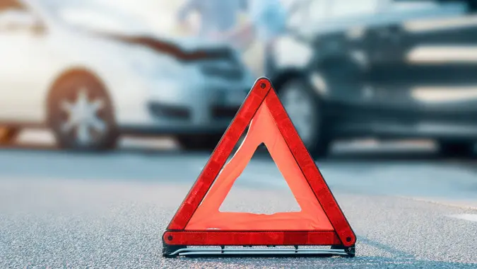 Two men reporting a car crash for the insurance claim,main focus on red triangle.