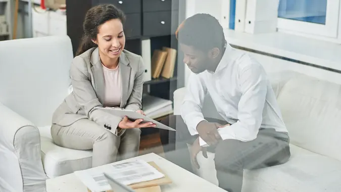 Positive confident pretty businesswoman showing clipboard with agreement to phantom client in modern comfortable office.