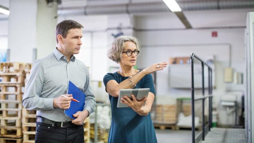 Manager discussing with male worker at printing plant.