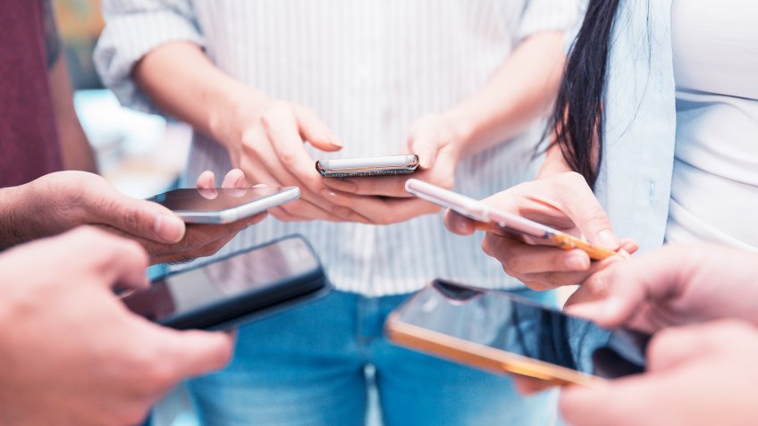 Group of people holding their smartphone and testing a mobile app.