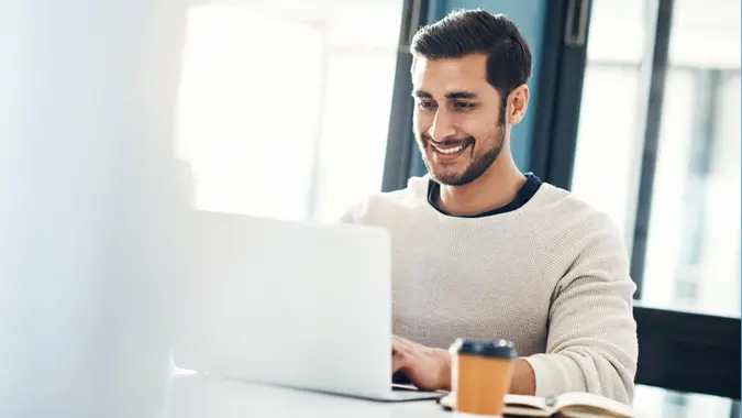 Shot of a young businessman using a laptop at his desk in a modern office.