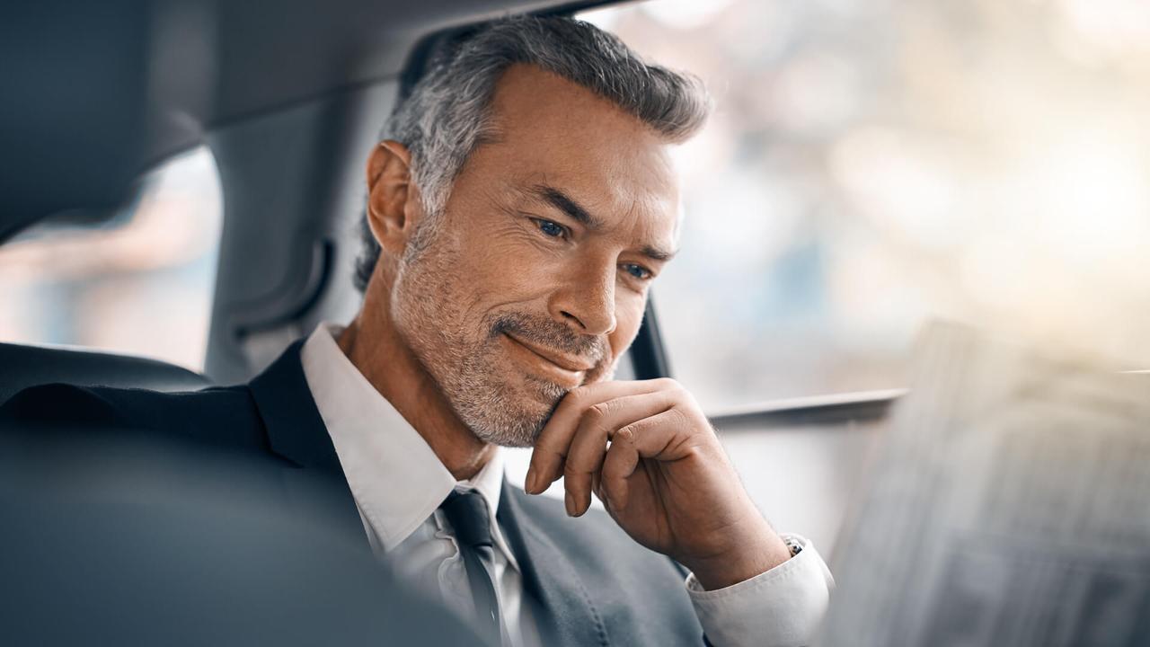 Cropped shot of a handsome mature businessman reading the paper while sitting in the backseat of a car during his morning commute.